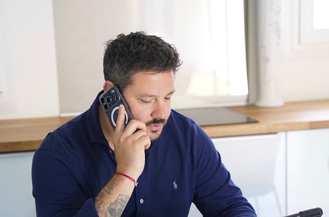 Homme en chemise bleue passant un appel professionnel dans un bureau lumineux