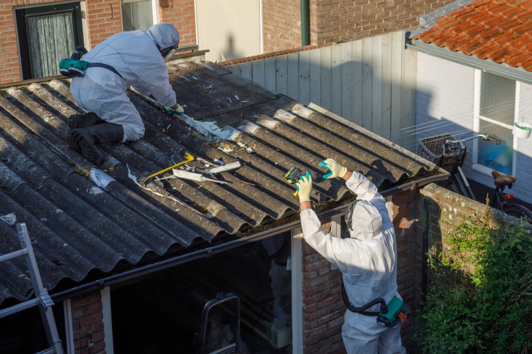 Techniciens protégés retirant des plaques amiantées sur une toiture
