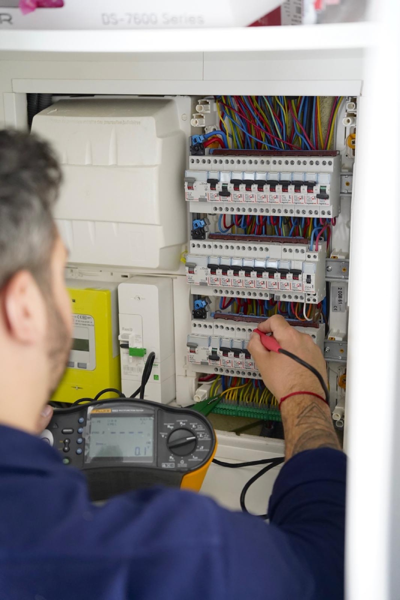 Électricien contrôlant un tableau électrique avec un multimètre