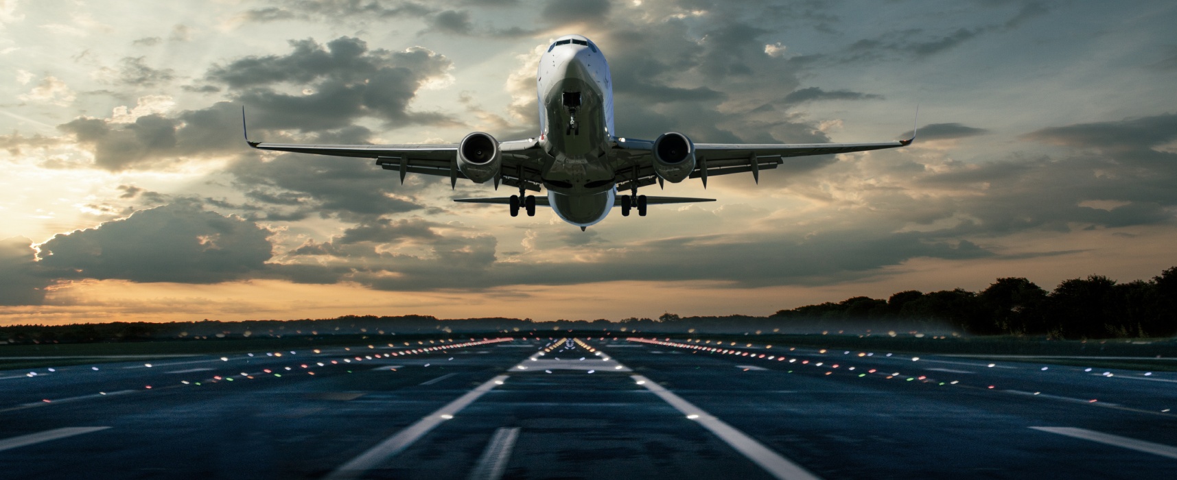 Avion de ligne décollant au coucher du soleil sur une piste éclairée