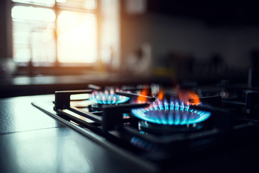 Flammes bleues d'une gazinière allumée dans une cuisine ensoleillée